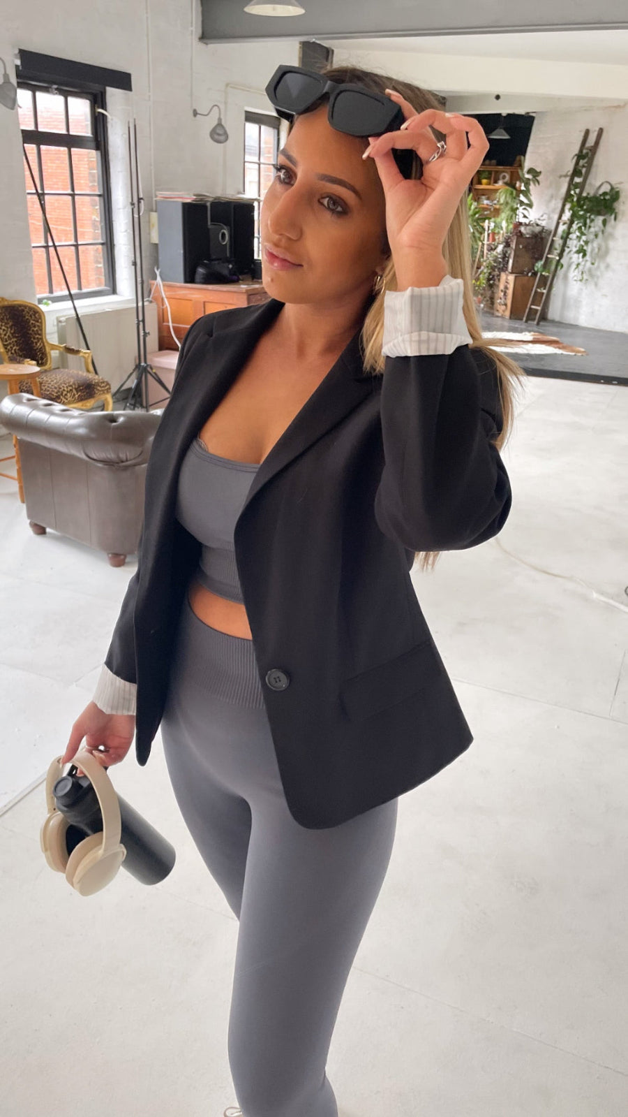 Lady with a grey gym set but also wearing it with bLazer making the set sleek and different
