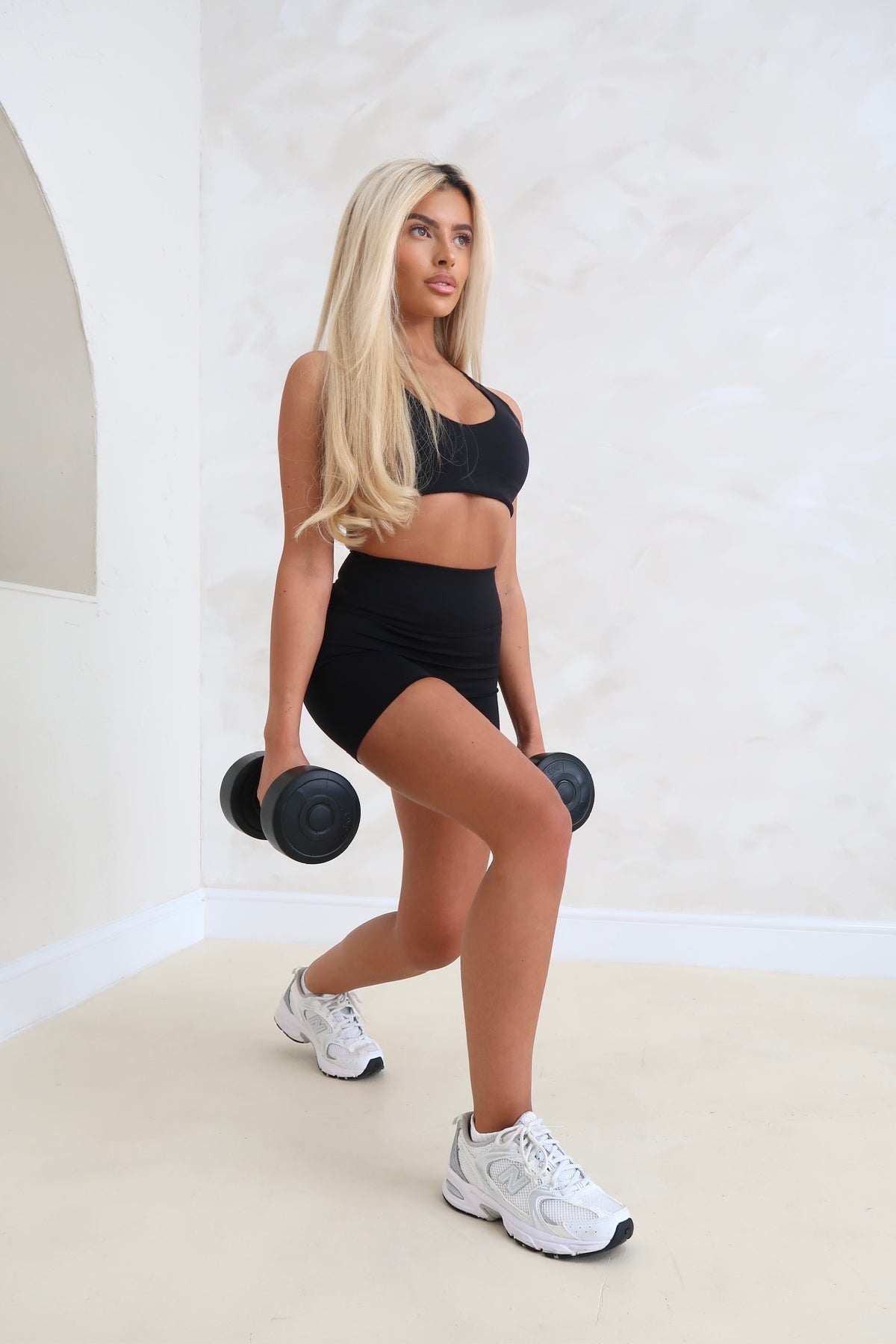 Woman exercising with dumbbells in a minimalistic indoor setting