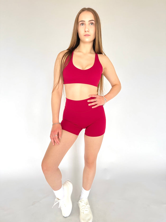 Woman wearing a red sports outfit on a plain background