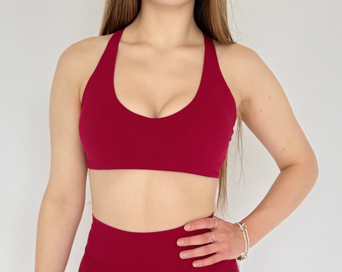 Person wearing a red sports bra and leggings on a plain background