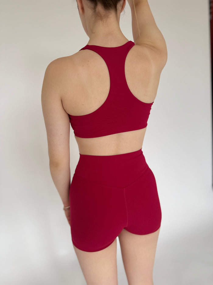 Person wearing a red sports bra and shorts set against a plain background