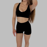 Woman wearing a black sports bra and shorts on a white background