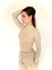 Woman wearing a beige long-sleeve top and pants on a white background